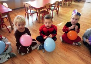 Dzieci siedzą z balonikami